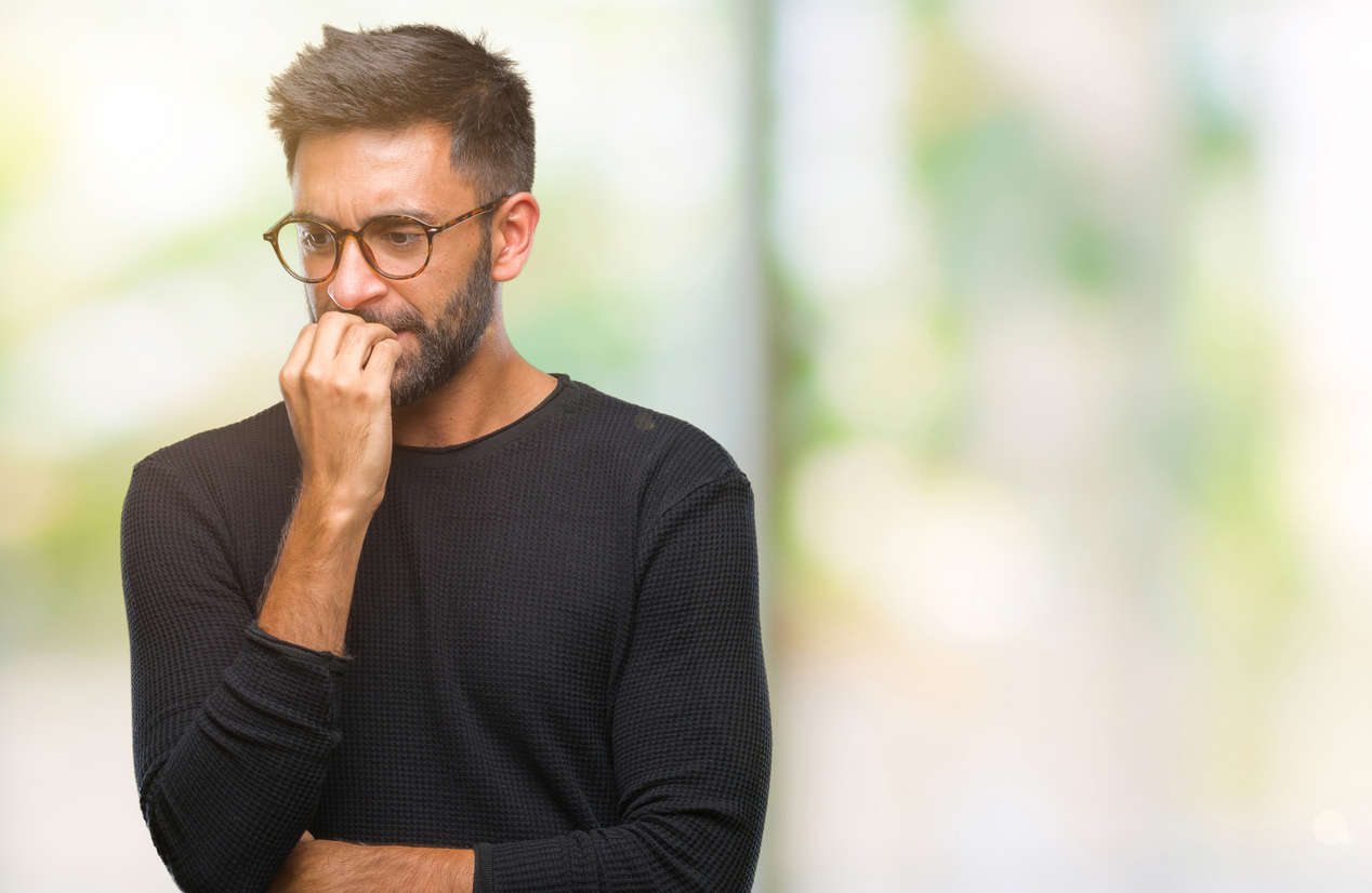 a man wearing glasses and biting his nails looking anxious