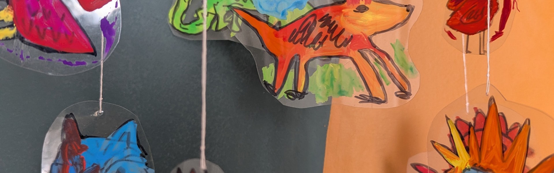 Main image: a handmade mobile, with quirky drawn and painted figures on acetate sheets. 
