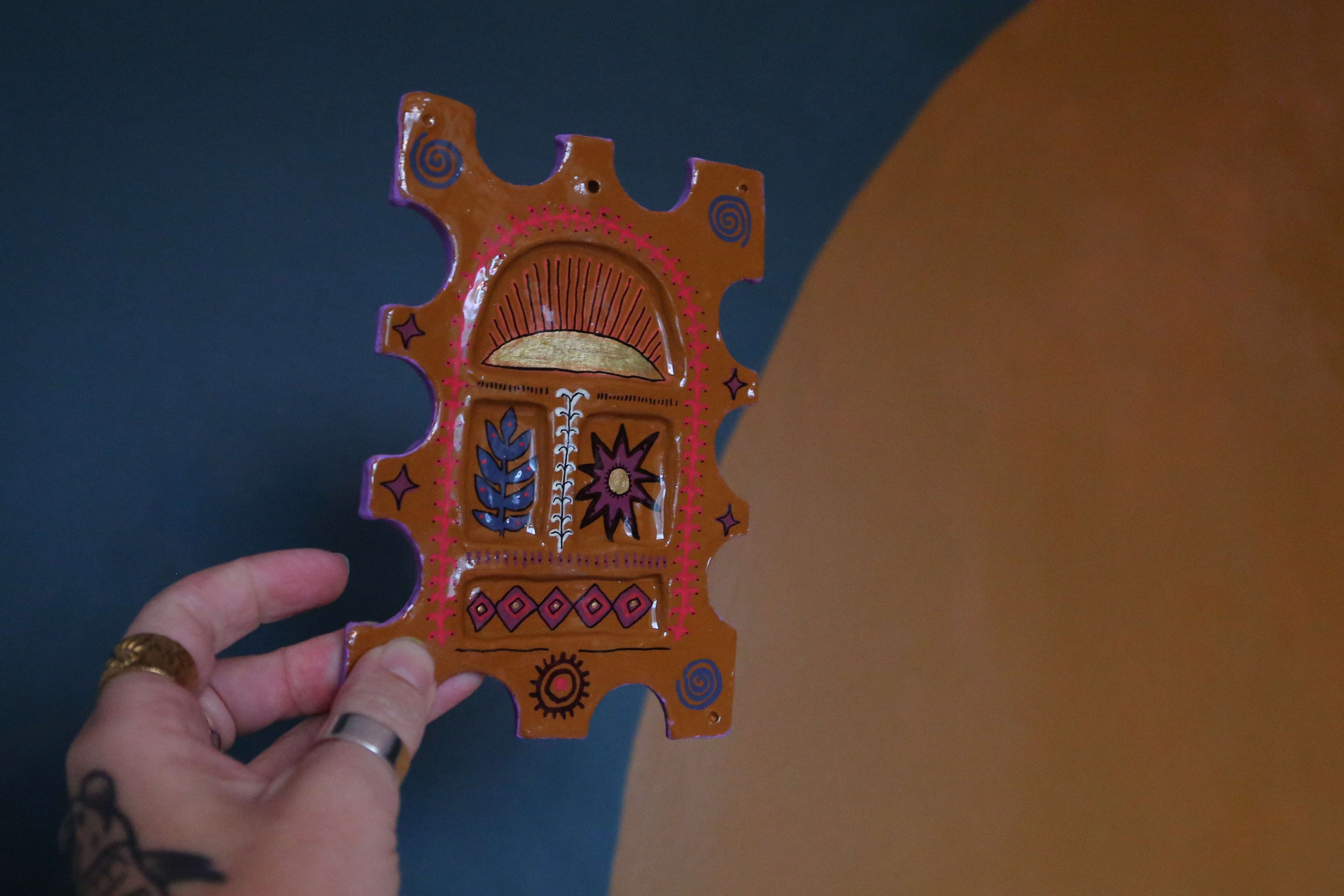 Main image: an air dry clay trinket dish, painted brown, with red, blue and purple funky patterns.