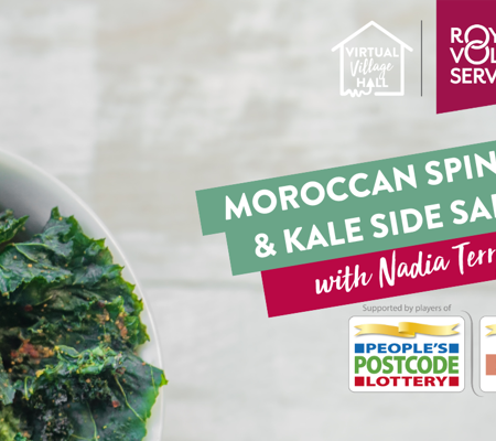 A bowl of crispy kale salad garnished with Moroccan seasoning on a white table.