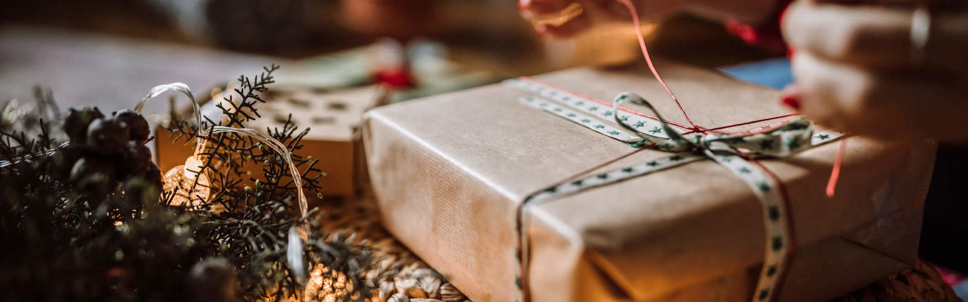 a person wrapping a Christmas present under a Christmas tree