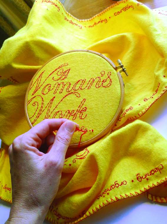 A close up of a yellow household duster being embroidered with red thread as part of Vanessa Marr's Domestic Dusters project