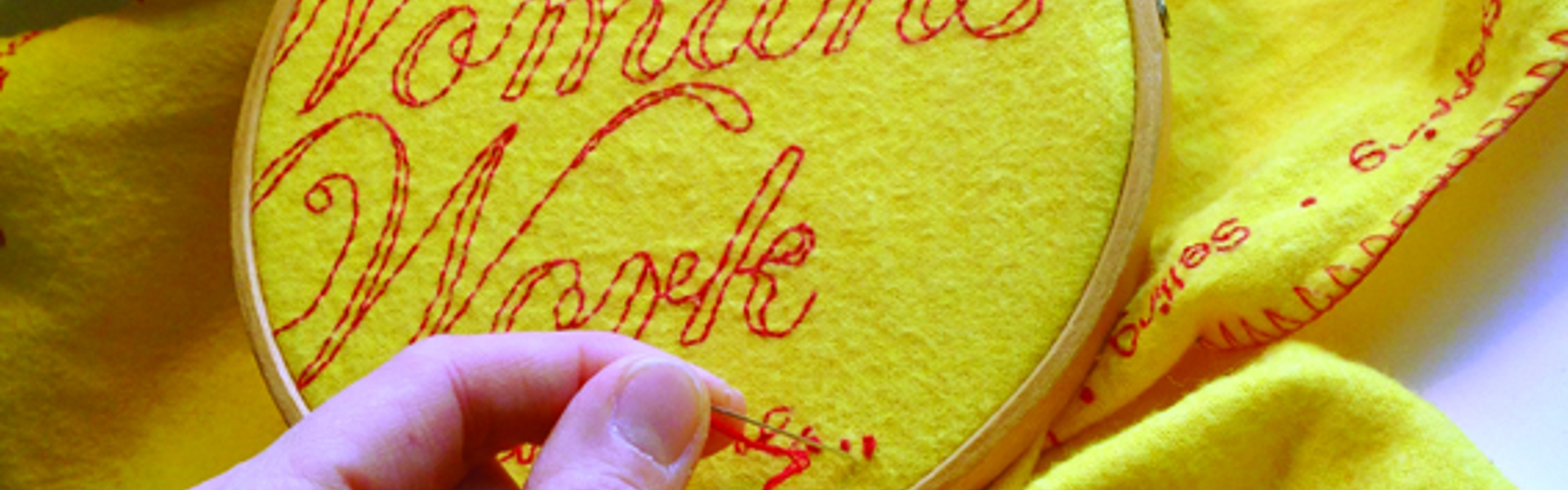 A close up of a yellow household duster being embroidered with red thread as part of Vanessa Marr's Domestic Dusters project