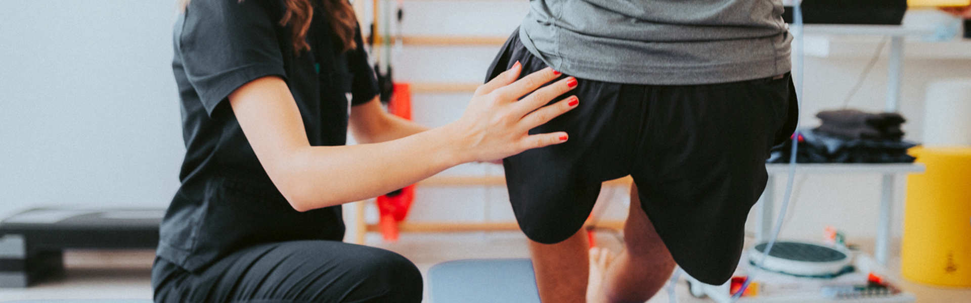 a female trainer assisting a man into a pistol squat position