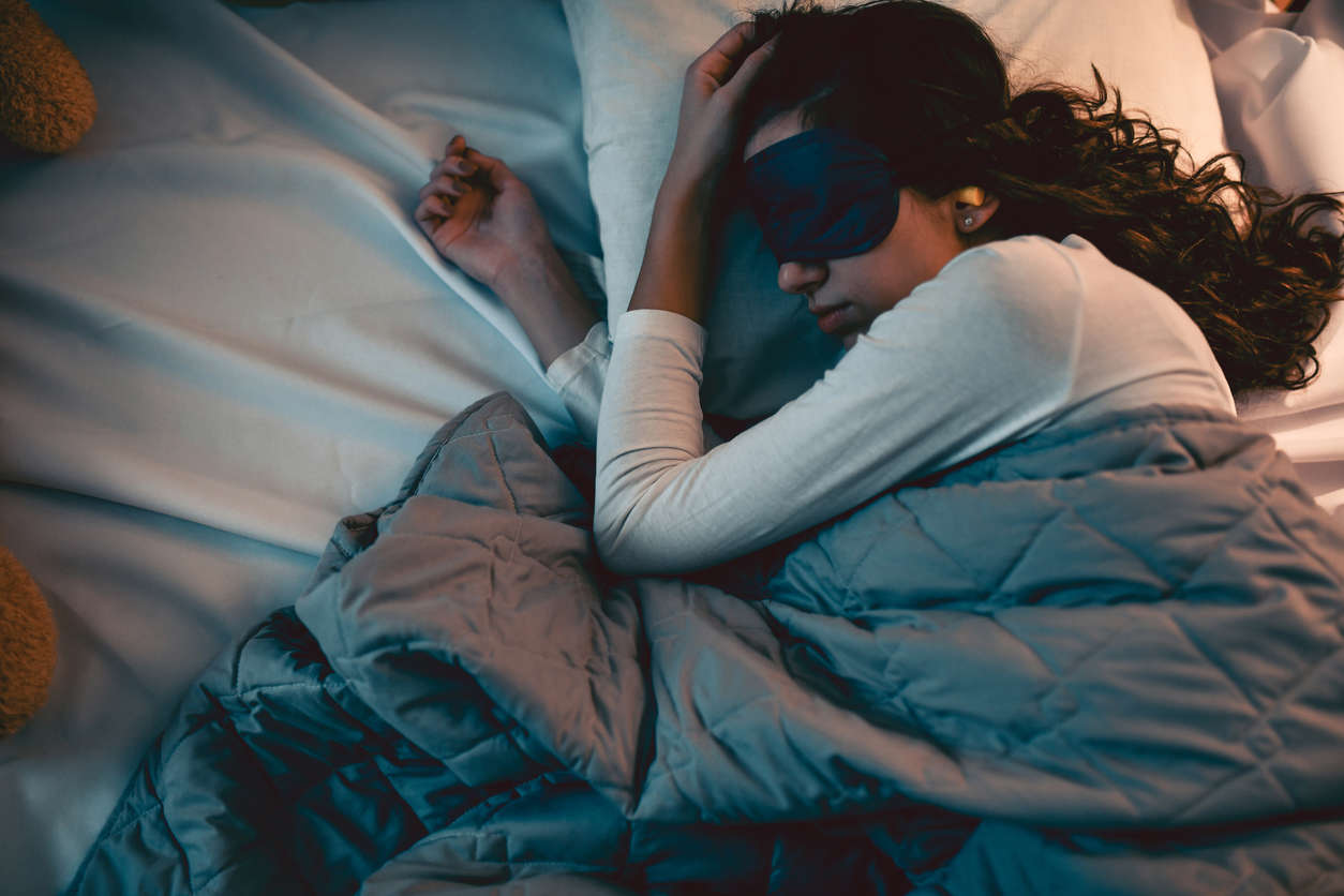 a woman sleeping in bed with a back sleep mask on it