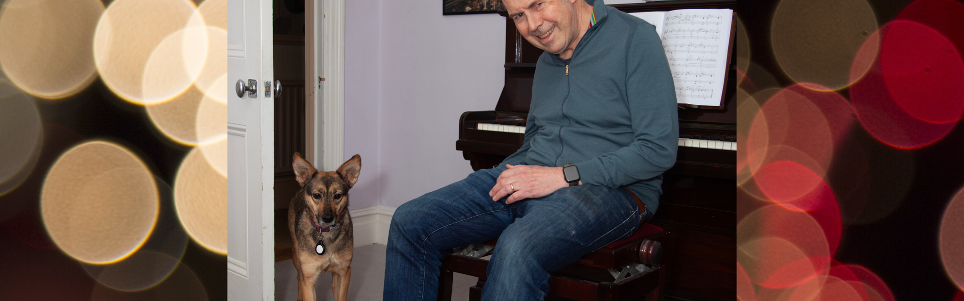 A photo of Rory Cellan-Jones and his rescue dog Sophie, from Romania. Rory is sat in front of a piano, with Sophie walking into the room. With a background image of gold and red orbs on a black background.