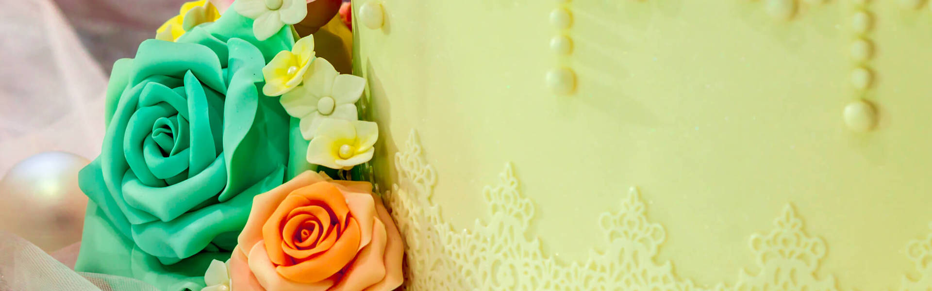 a close up of a cake covered with green sugar paste and decorated with green orange and yellow sugar paste roses