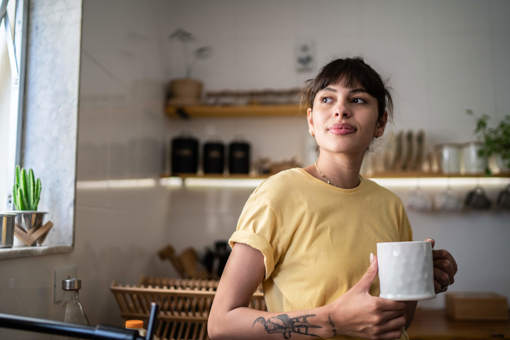 a woman in a yellow tshirt holding a white mug of tea