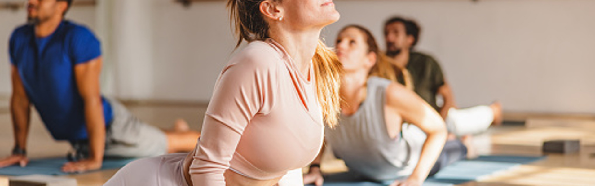 a woman wearing yoga clothes lying on a yoga mat doing a cobra pose