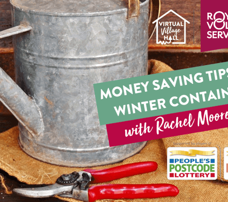 a watering can and red garden sheers and a garden trowel laid out on a wooden table against a brick wall