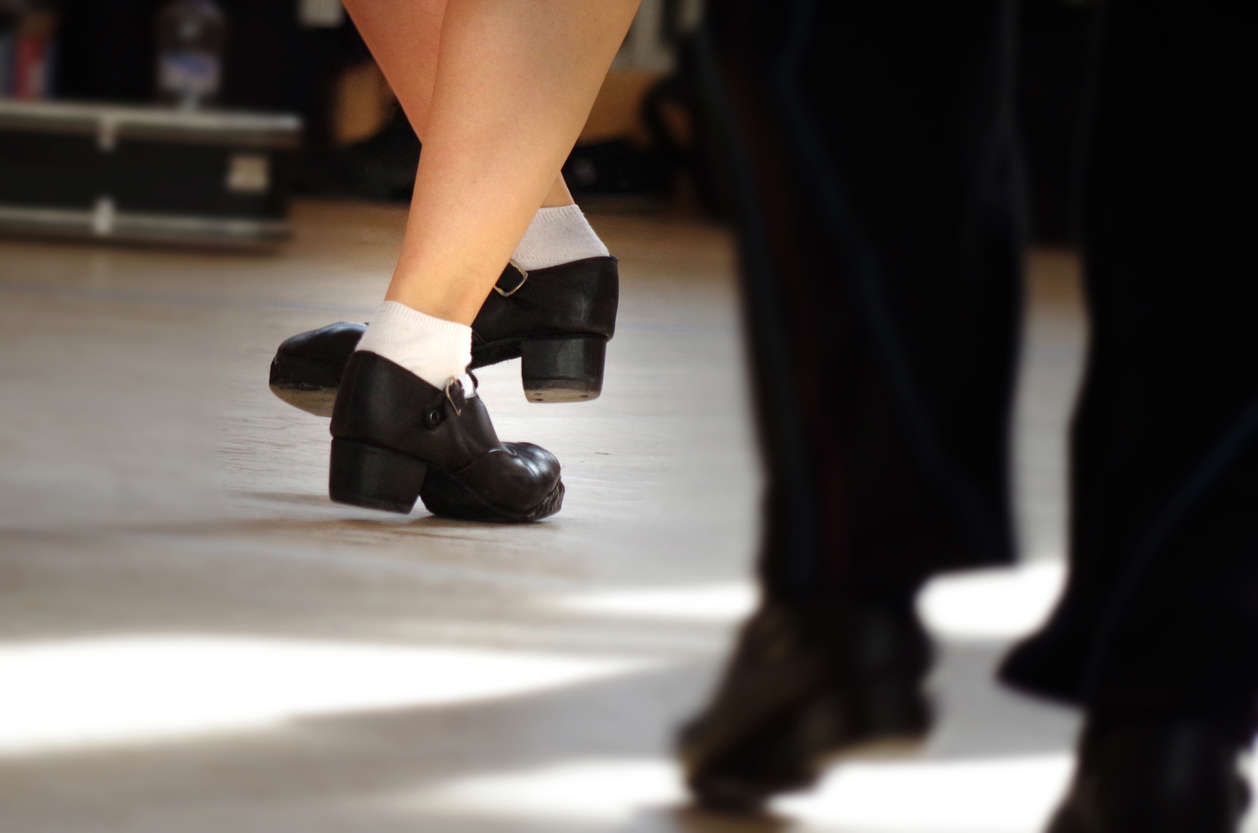 a close up of a dancer wearing traditional black Irish dancing shoes and white socks