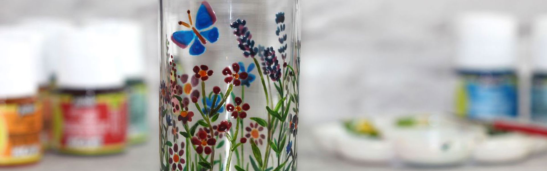Main image: hand painted floral design with a blue butterfly from Kate's painting on glassware for beginners session.
