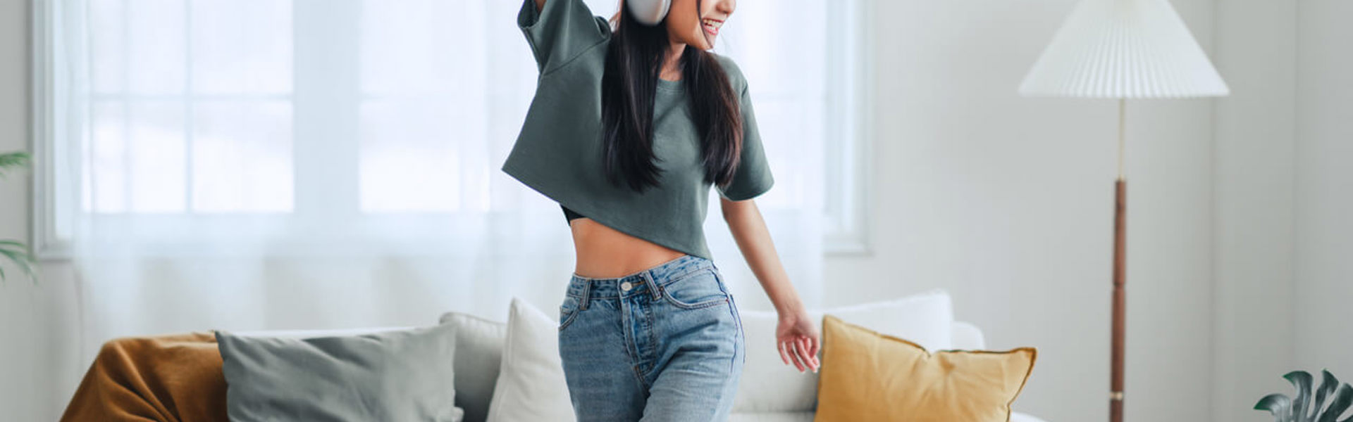 a girl wearing white headphones dancing in a living room