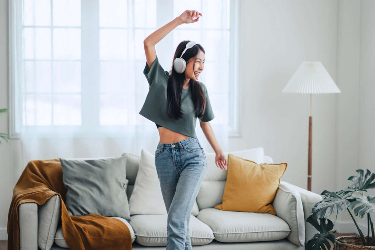 a girl wearing white headphones dancing in a living room