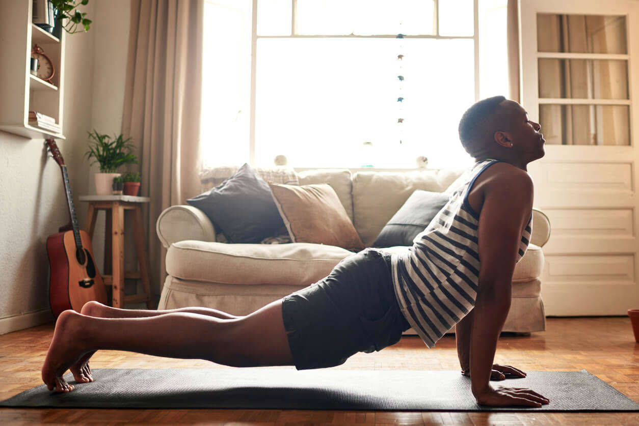 a man doing cobra pose on a yoga mat at home in the living room