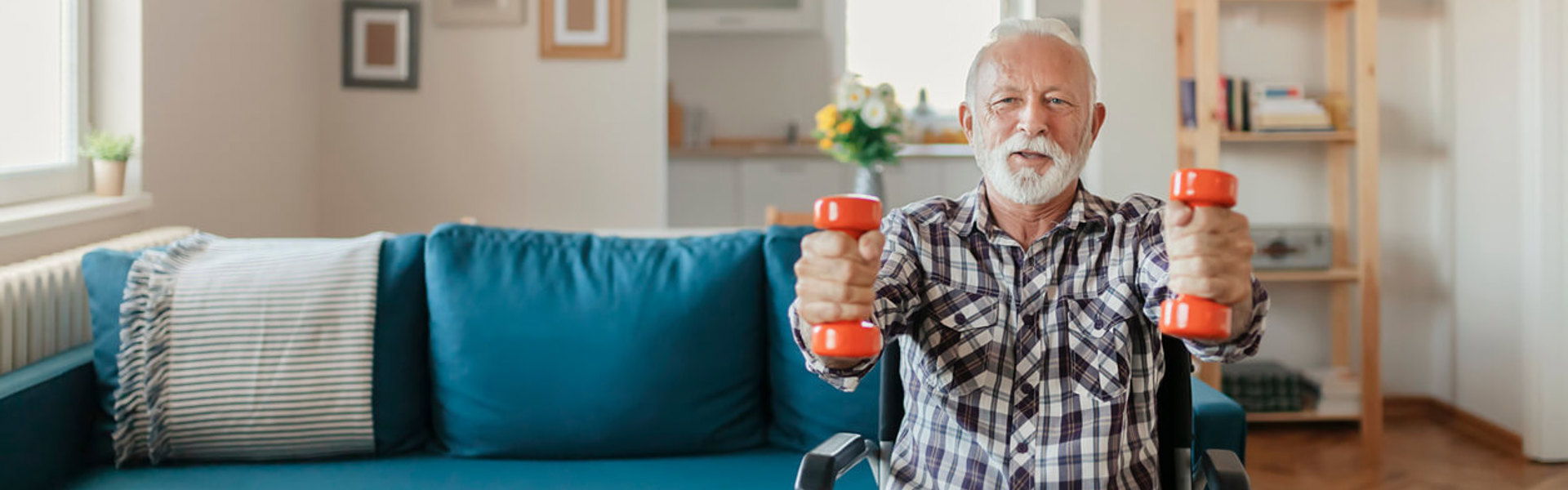 a man sat in a wheel chair using orange hand weights