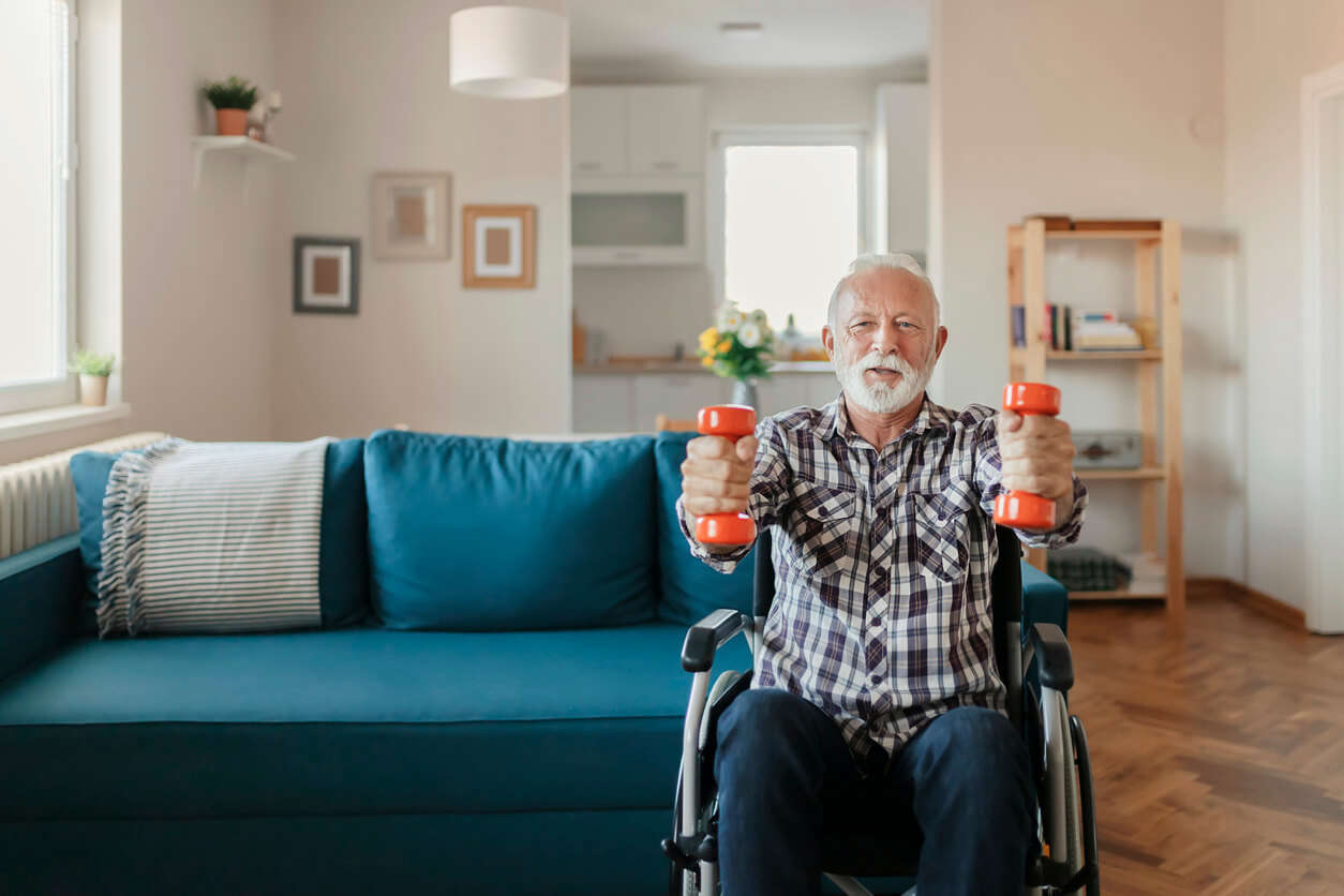 a man sat in a wheel chair using orange hand weights