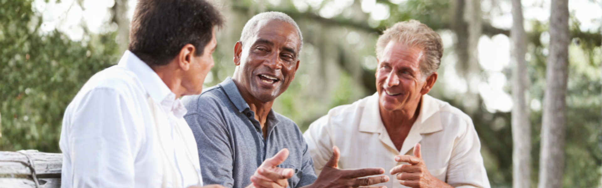 Main image: three men sat on a bench out in nature, smiling, discussing men's health.