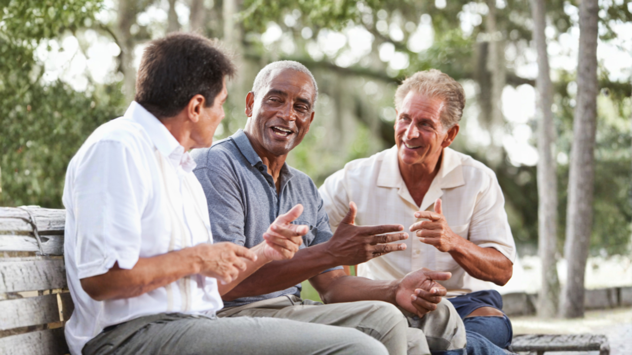 Main image: three men sat on a bench out in nature, smiling, discussing men's health.