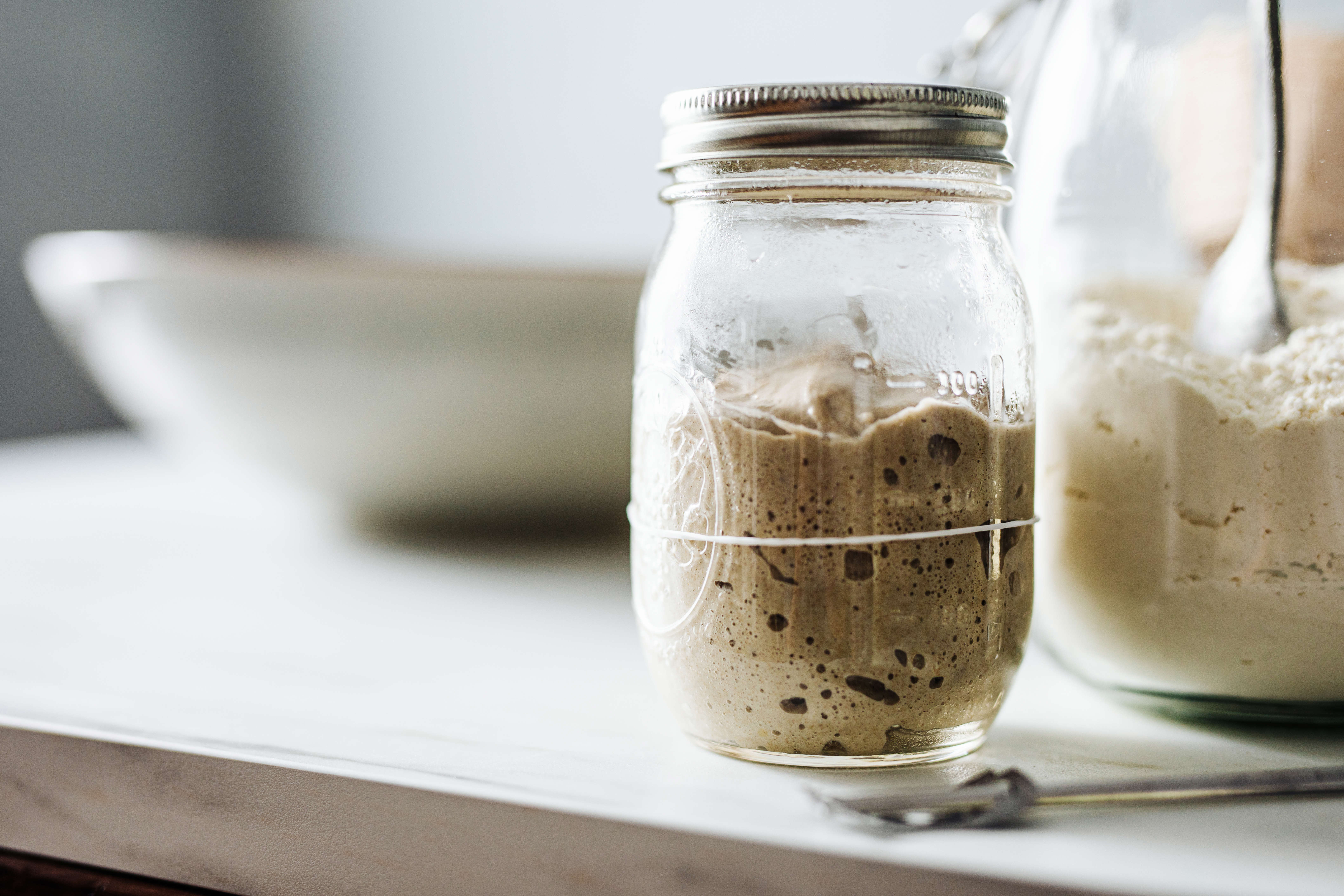 a jar of sourdough starter on a white kitchen countertop