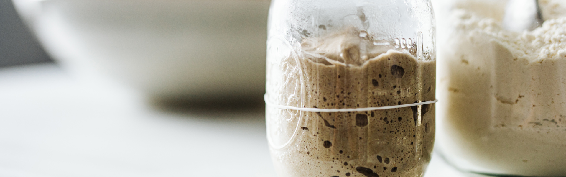 a jar of sourdough starter on a white kitchen countertop