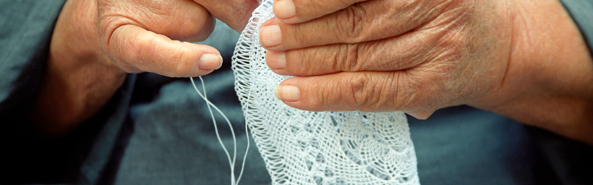 a close up of someone using a needle and thread to sew a white doily decoration