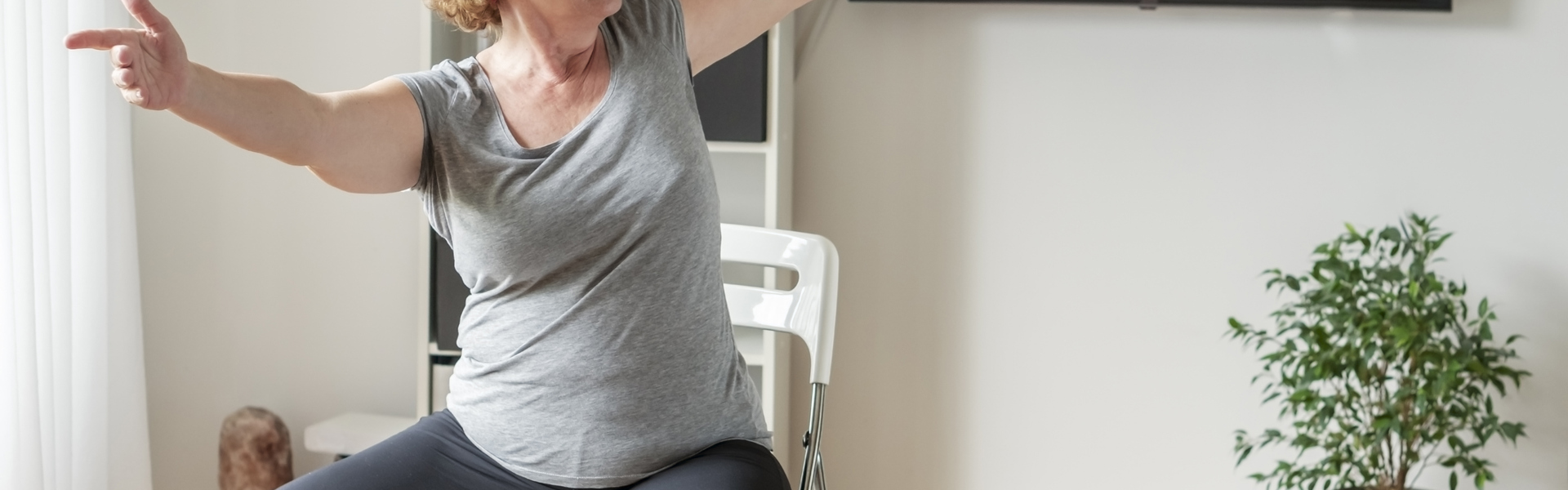 Woman seated on a chair twisting her body and stretching her arms