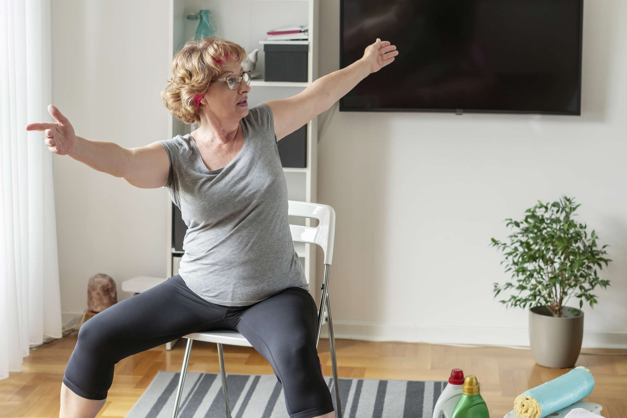 Woman seated on a chair twisting her body and stretching her arms