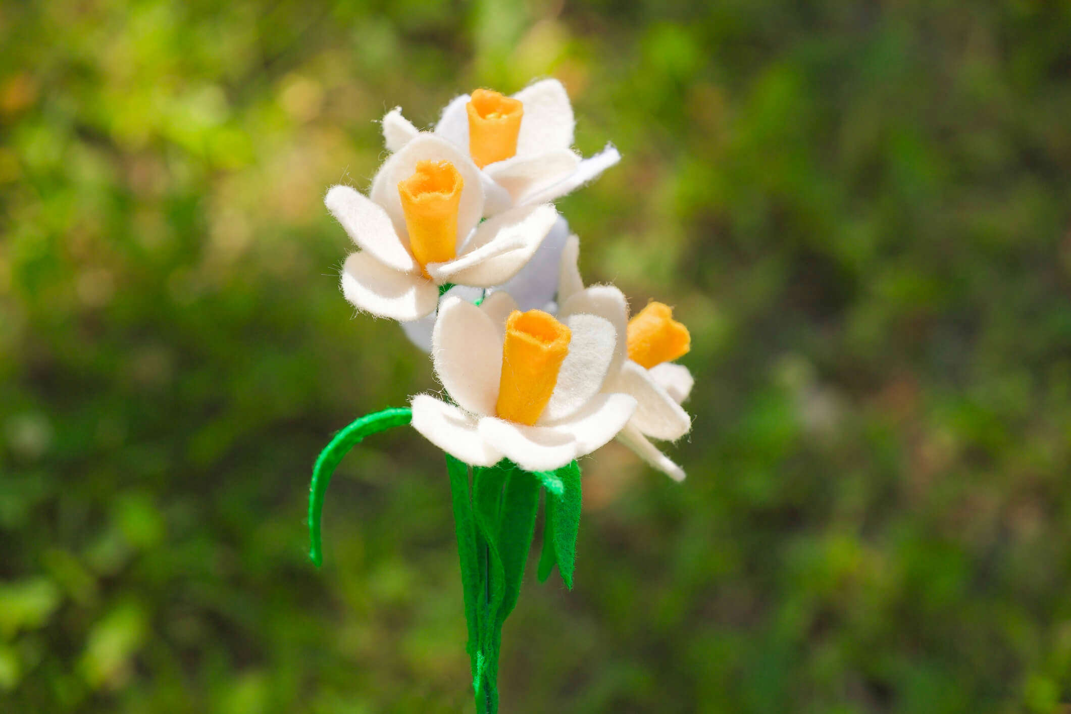 a bunch of felt daffodils on a green leaf background