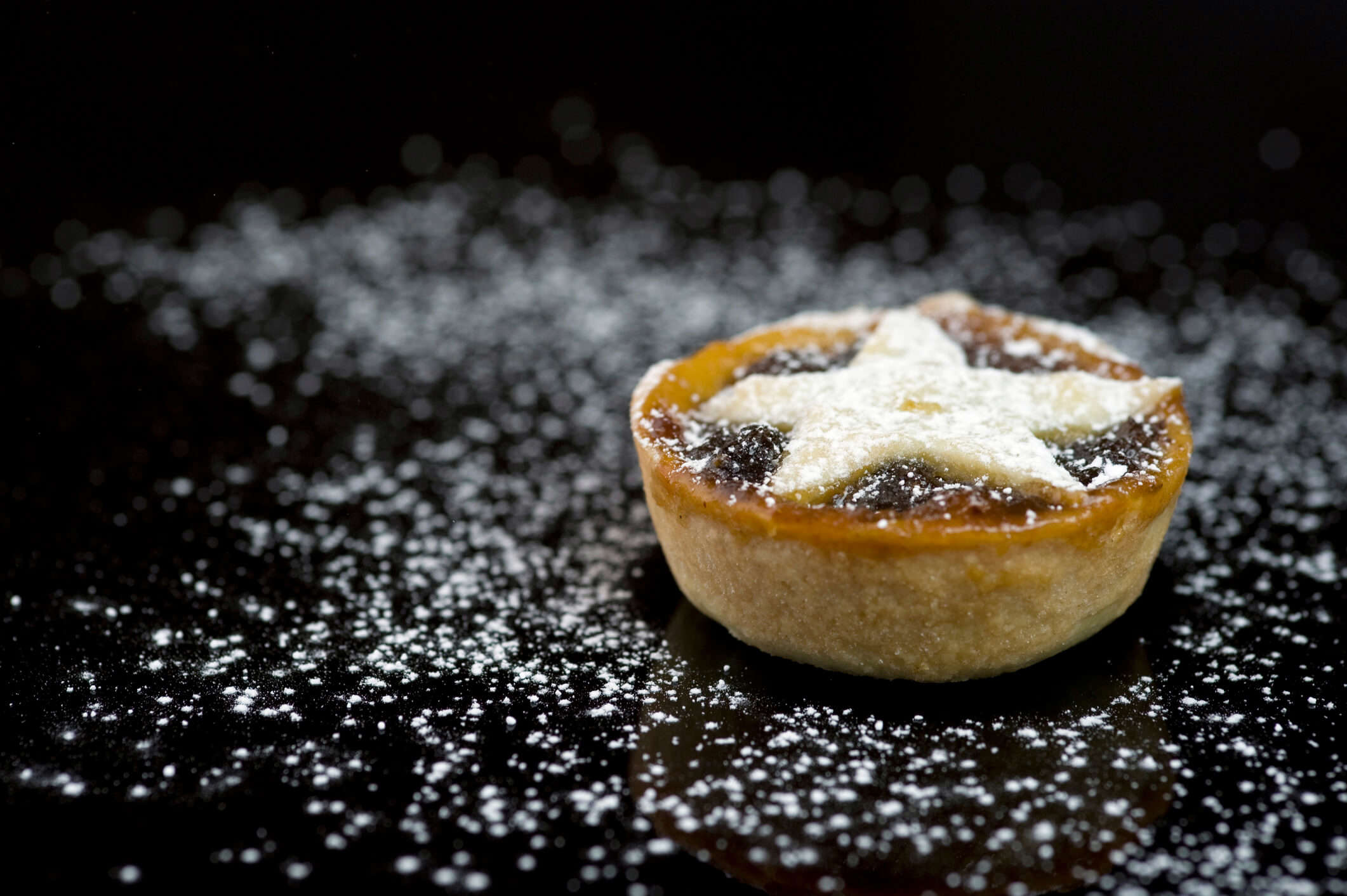 a close up of a mini mince pie with a star shaped top dusted with icing sugar