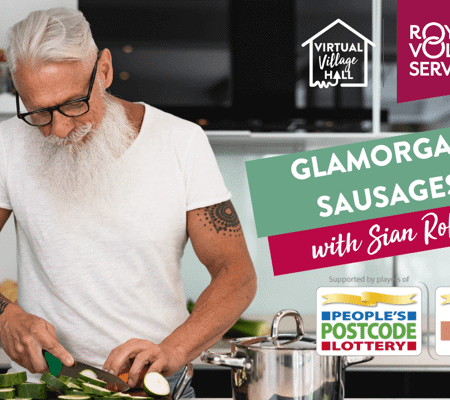 a man with a beard and glasses in a white t-shirt slicing courgette in a kitchen