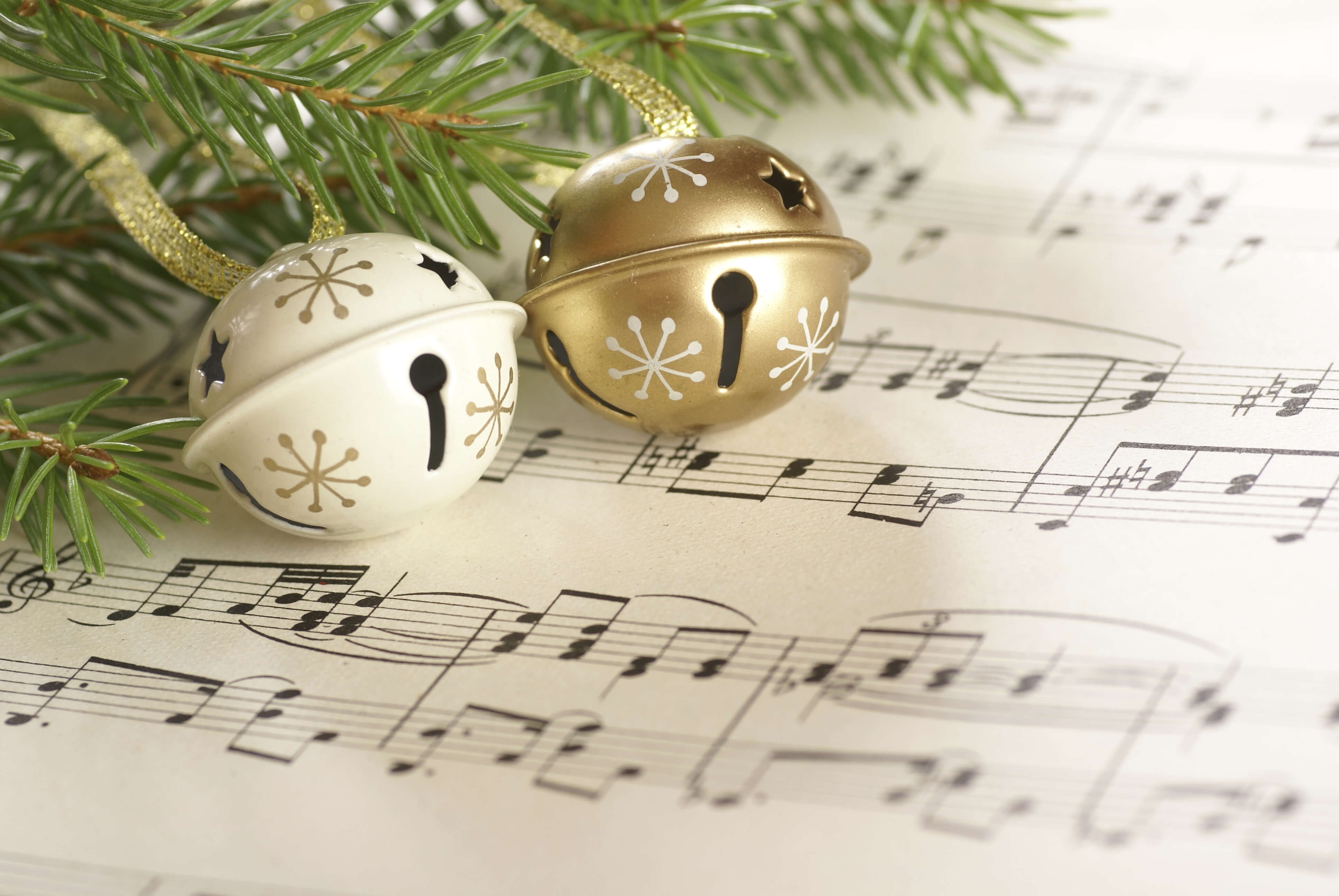 two Christmas bells on a sheet of music 