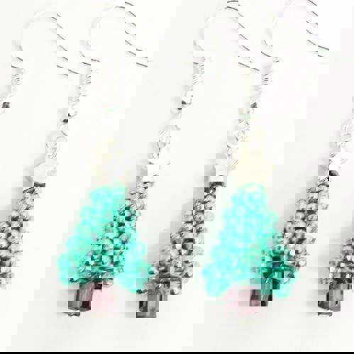 A close up of a pair of two green festive Christmas tree earrings