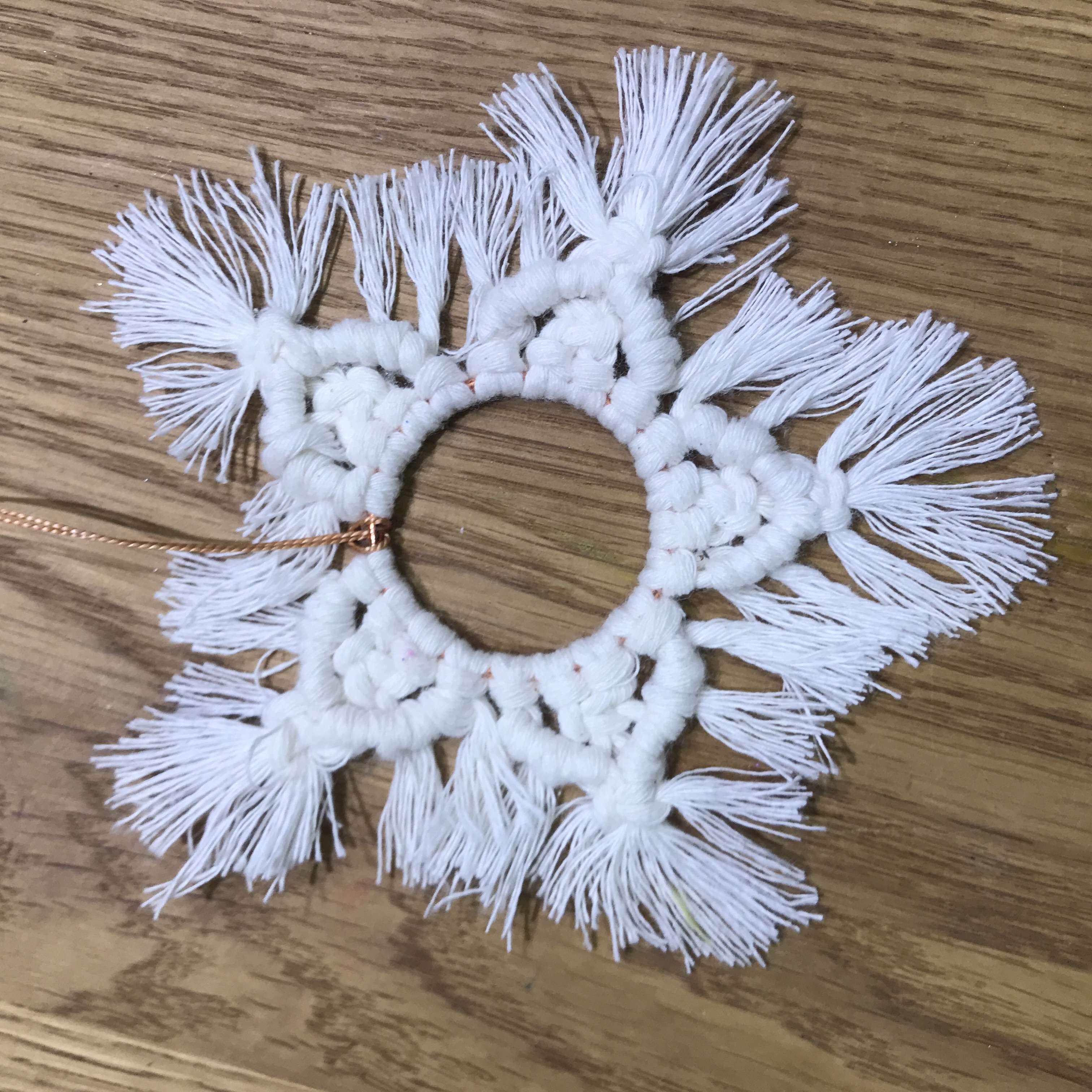 A handmade white macramé star on a wooden table