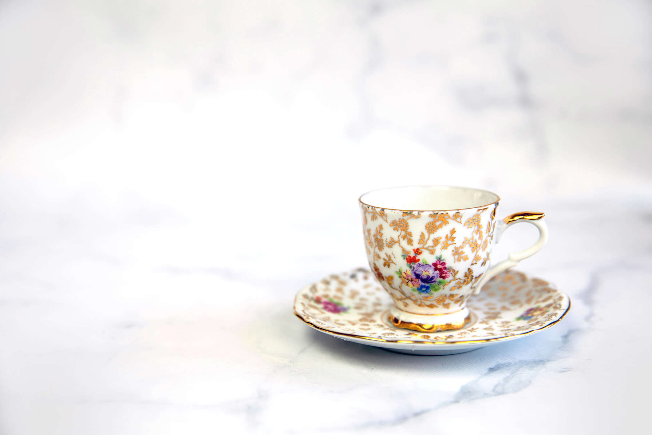a decorative floral teacup on a saucer on a white background