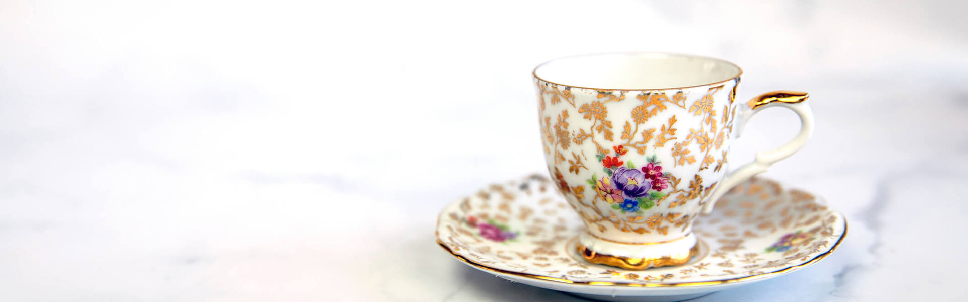 a decorative floral teacup on a saucer on a white background