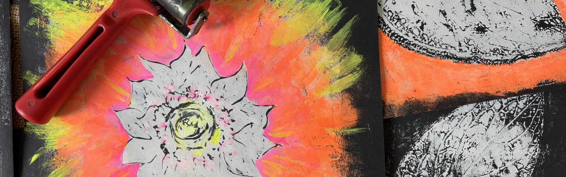 Main Image: A selection of monoprints, on dark paper with neon orange, yellow, pink and silver paints, with a red printing roller.