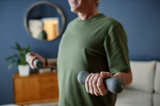 A person exercising in their living room using small, 2kg grey dumbbells.