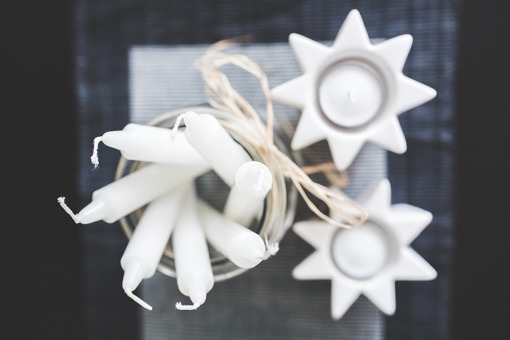 Main image: close up photo from above of tall candles and tealights in star shaped tealight holders.