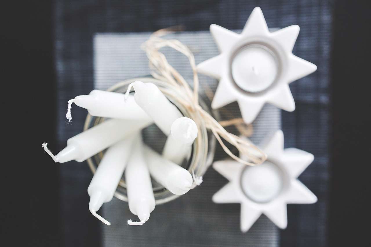 Main image: close up photo from above of tall candles and tealights in star shaped tealight holders.