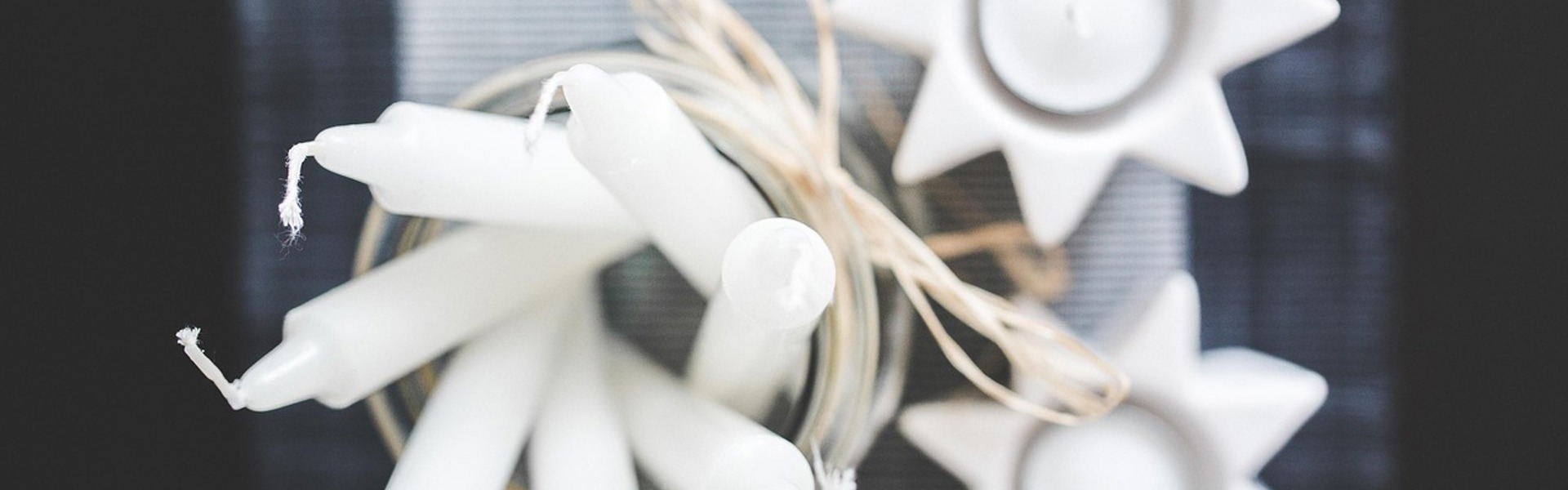 Main image: close up photo from above of tall candles and tealights in star shaped tealight holders.