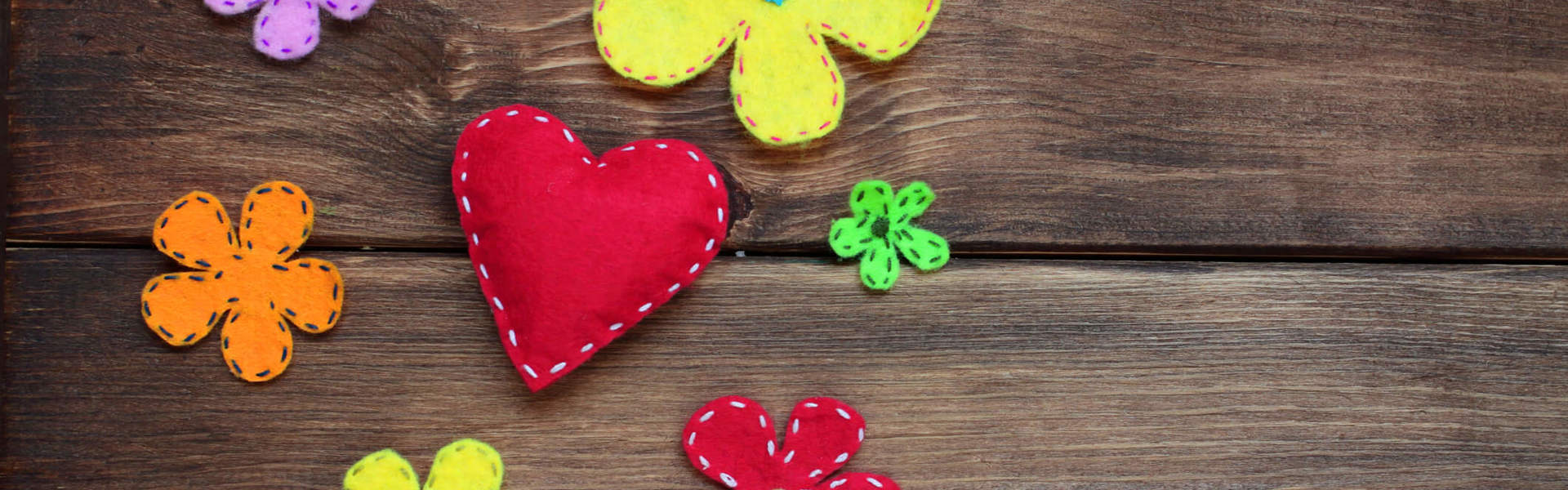 various felt flowers and heart shapes on a wooden background