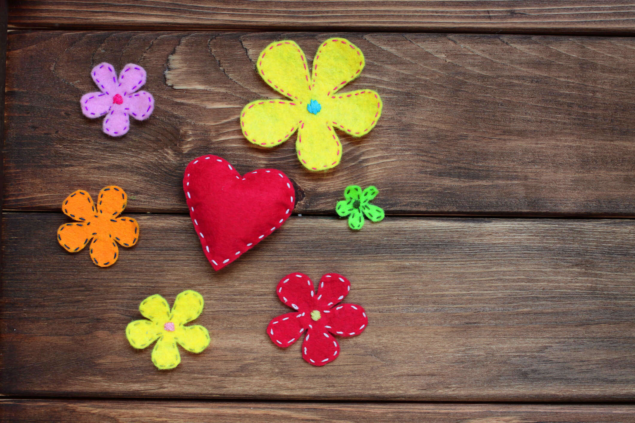 various felt flowers and heart shapes on a wooden background