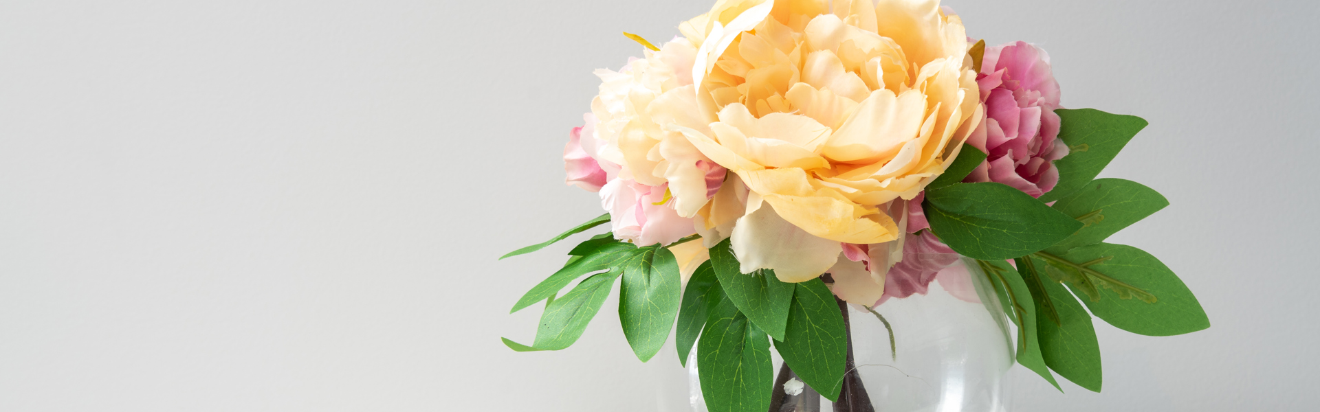 cut orange, pink and red peonies in a sphere shaped glass vase