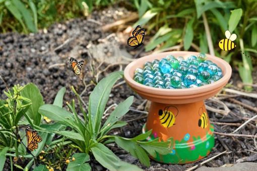 Main image: a DIY bee bath for the garden, made from a terracotta pot and saucer with marbles for the bees to land on. With cute yellow bees painted on the side.