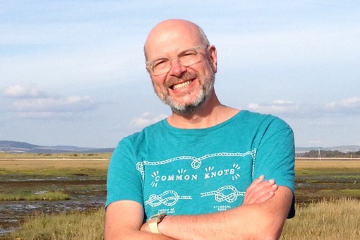 Main Image: a photo of Kim Pollard from the Men's Health Forum, standing in a sunny field, smiling wearing a blue t-shirt