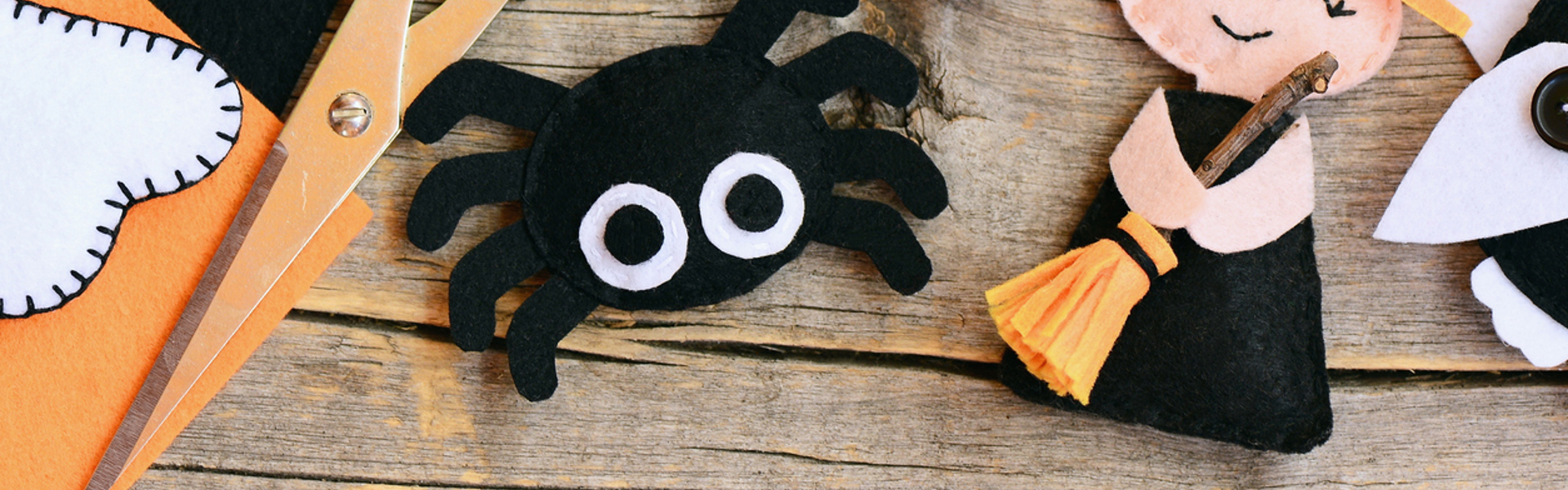 a close up of a fabric halloween spider craft on a wooden table surrounded by craft tools