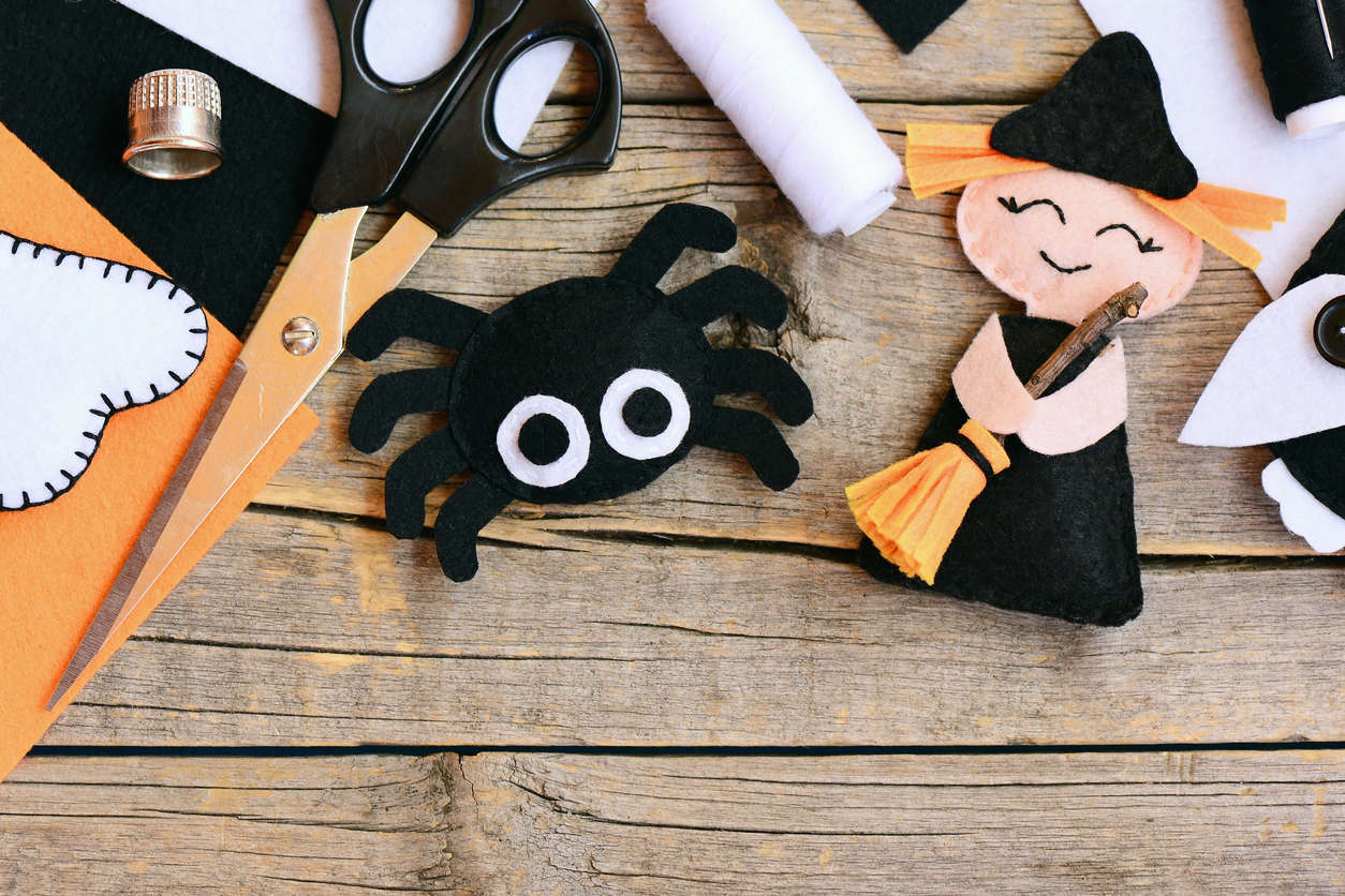 a close up of a fabric halloween spider craft on a wooden table surrounded by craft tools