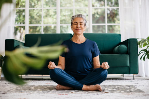 a woman sat cross legged with eyes closed in the living room