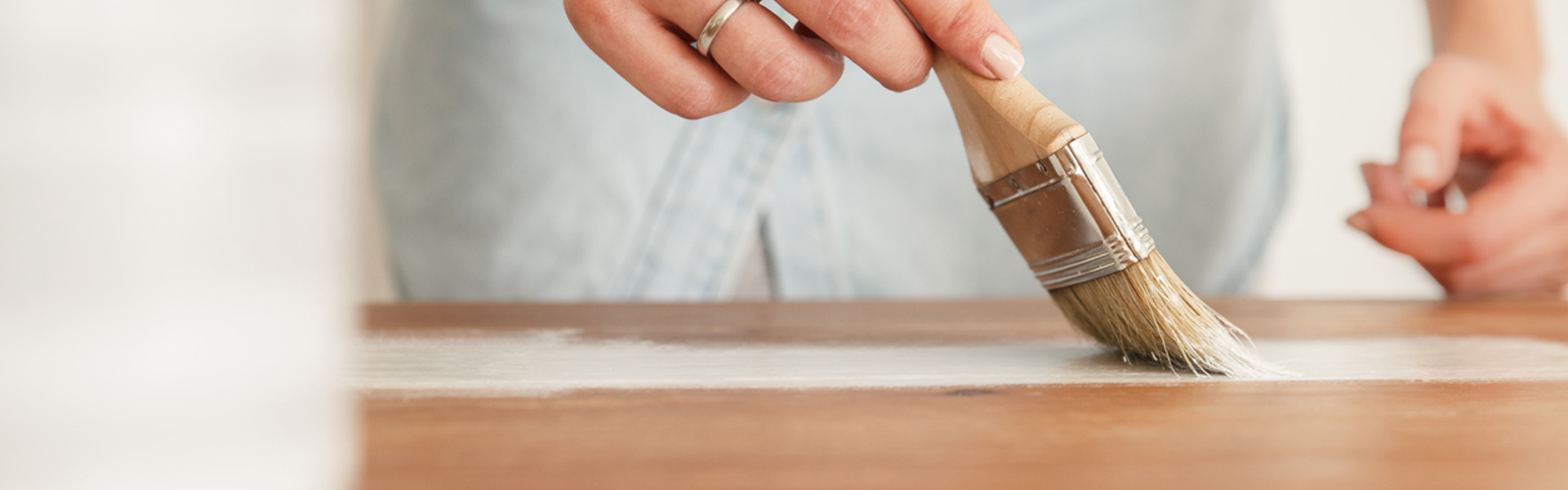 a close up of a person painting wood with a red paint brush